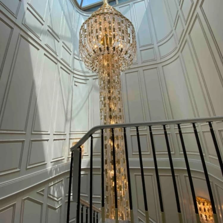 Long vertical chandelier extending through a multi-level foyer