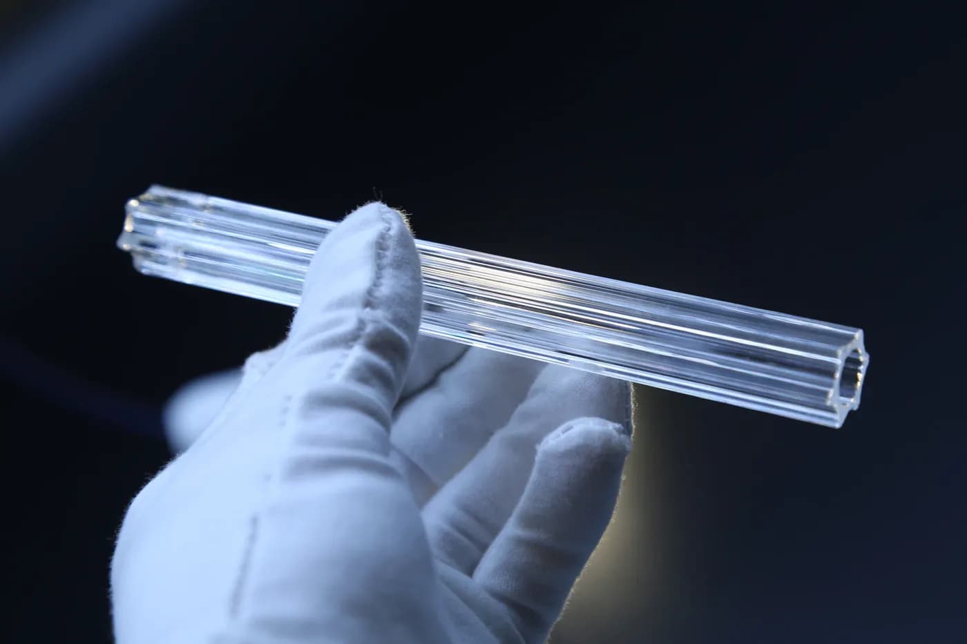 Clear crystal rod inspected by hand under controlled light